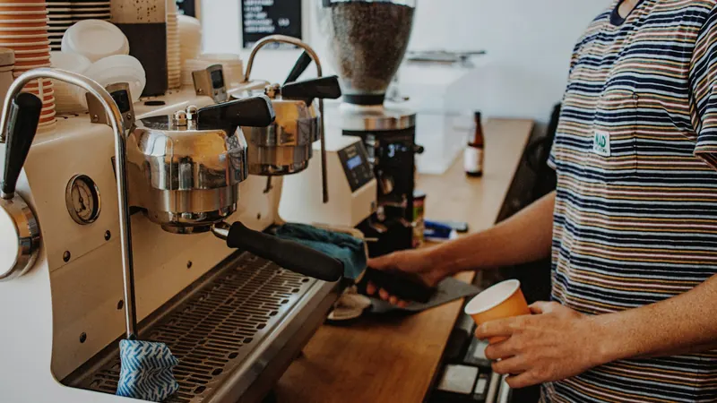 A barista preparing a drink at a café espresso machine