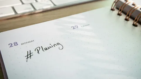A paper planner beside a keyboard for organising job applications